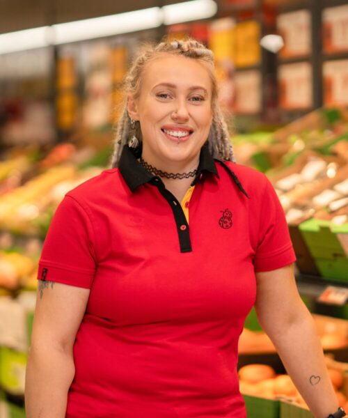 Kobieta w stroju służbowym na tle sklepu Biedronka.