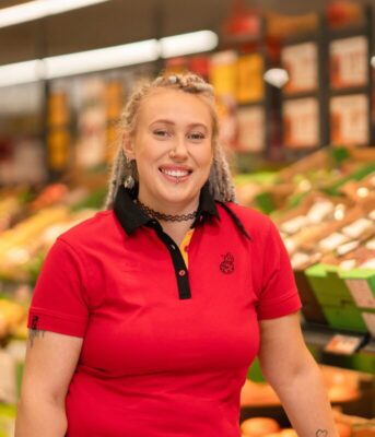 Kobieta w stroju służbowym na tle sklepu Biedronka.