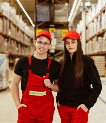 Pracownicy centrum dystrybucyjnego sieci Biedronka na tle magazynu.