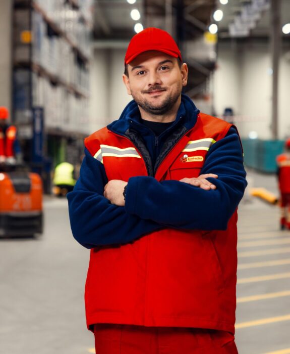 Pracownik centrum dystrybucyjnego biedronki na tle magazynu.