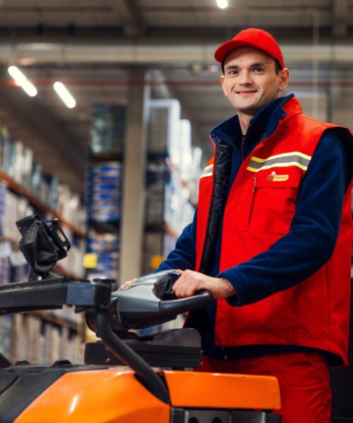 Pracownik centrum dystrybucyjnego biedronki prowadzący wózek widłowy.