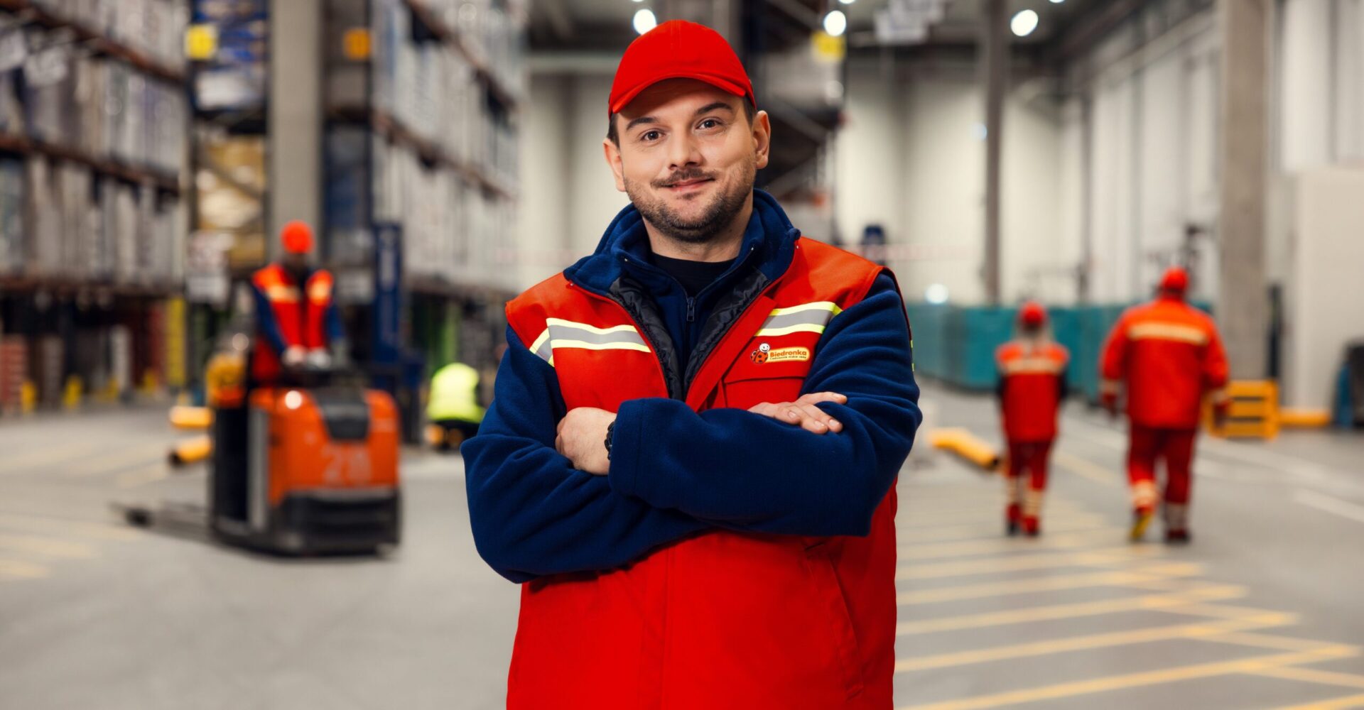 Pracownik centrum dystrybucyjnego biedronki na tle magazynu.