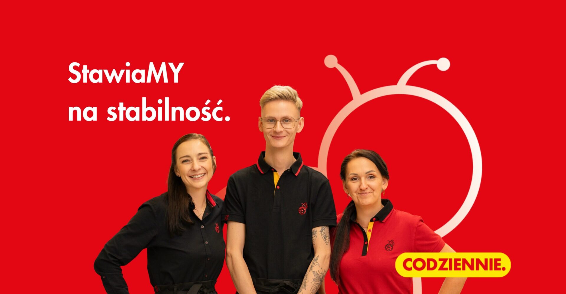 Trzy osoby ubrane w stroje służbowe Biedronki. Napis: Stawiamy na stabilność.