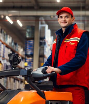 Pracownik centrum dystrybucyjnego biedronki prowadzący wózek widłowy.